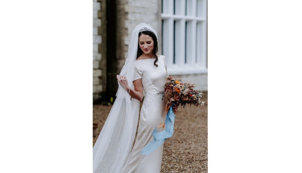 Bride Sophie adjusts her veil standing outside Langrish House.