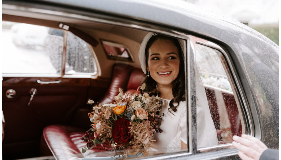 The bride Sophie smiles in the back of a Bentley after the ceremony.