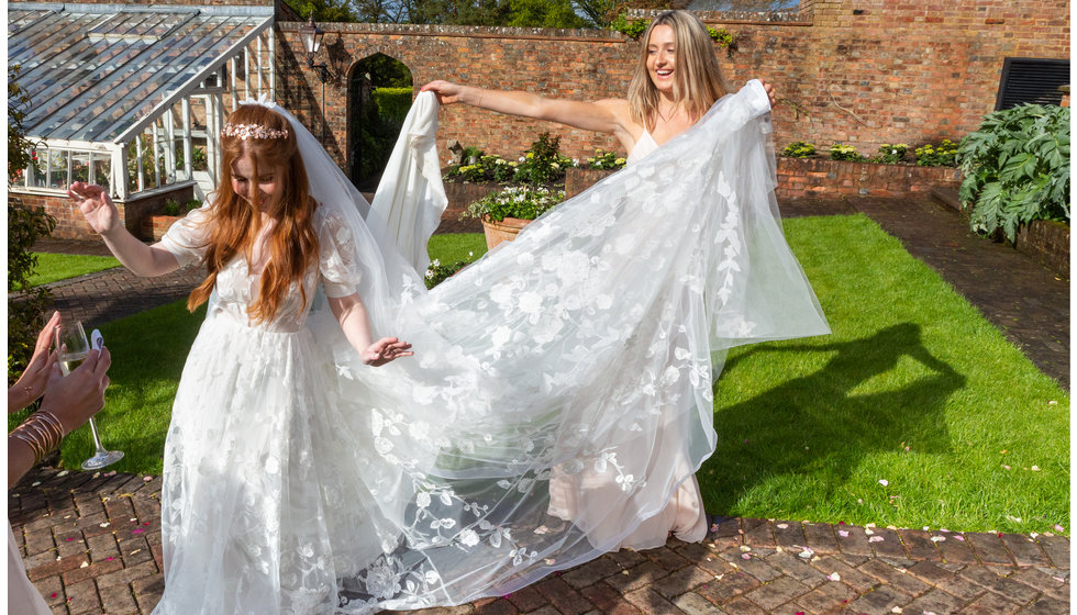 One of Sarah's bridesmaids helps Sarah with her train of her wedding dress.