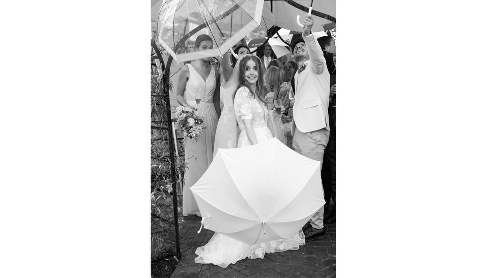 Sarah and a handful of her friends holding umbrellas in the rain.