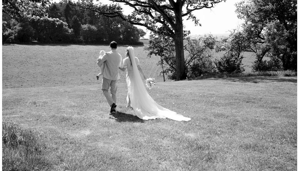 Charlotte & Harry's Magical Meadow Marquee Wedding in Oxfordshire: The newlywed couple walking in the meadow post wedding ceremony