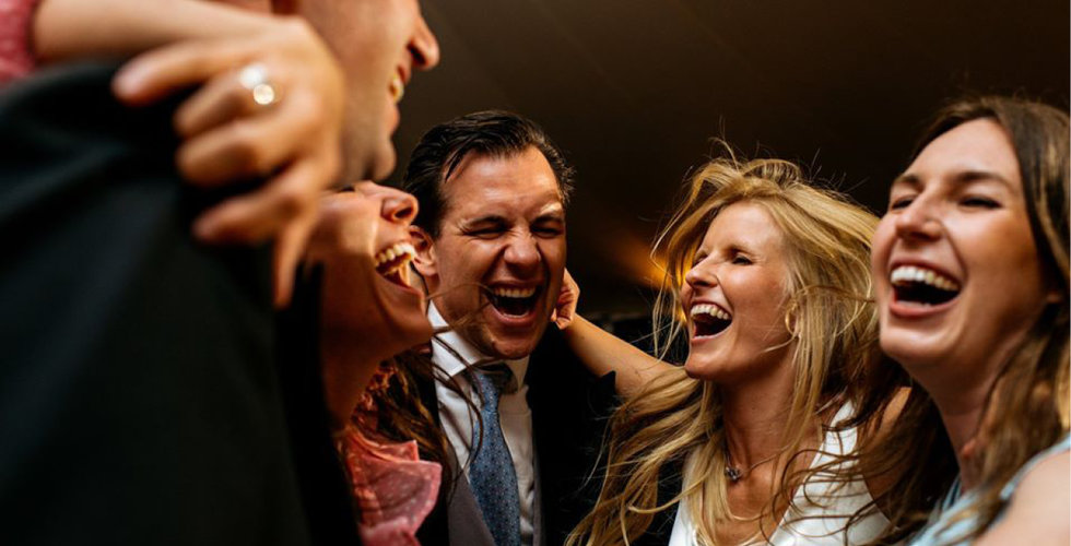 The bride and her friends all jumping together on the dancefloor.