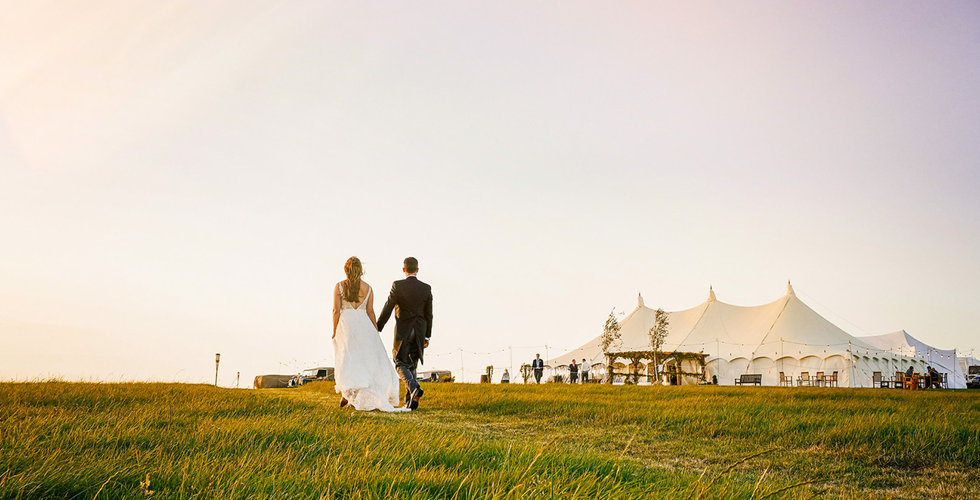 Josh and Victoria walking towards their traditional marquee.