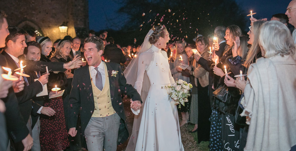 Bride and groom coming out of the Church surrounded by their guests throwing confetti at dusk.