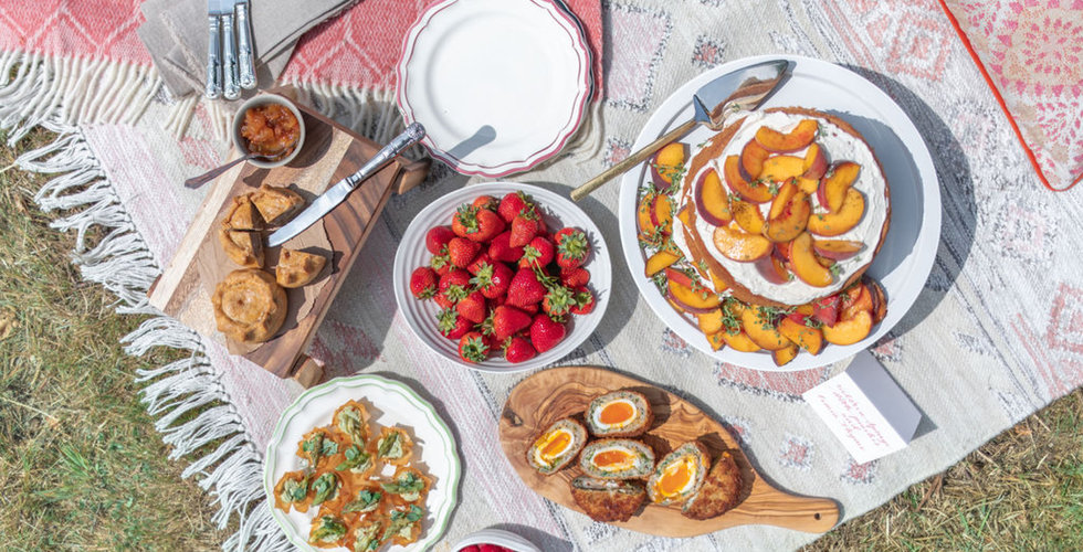 An overhead shot of a picnic all laid out on a big rug.