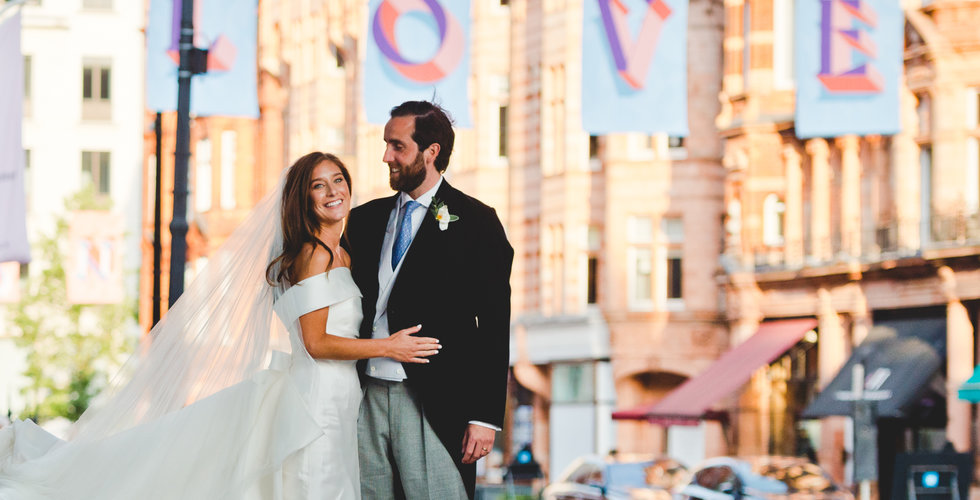 The bride and groom standing underneath a sign spelling LOVE in London.